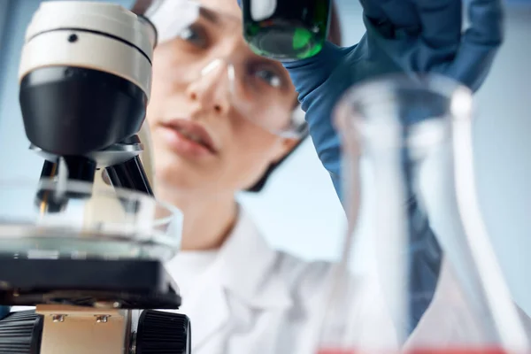 Kvinnlig laboratorieassistent mikroskop forskning bioteknik medicin — Stockfoto