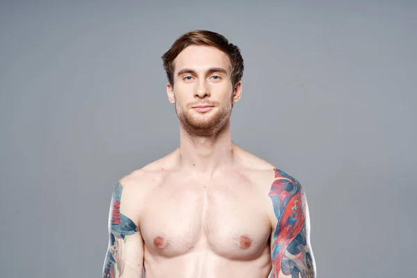Веселый мужчина с надутой мускулистой татуировкой на руках — стоковое фото