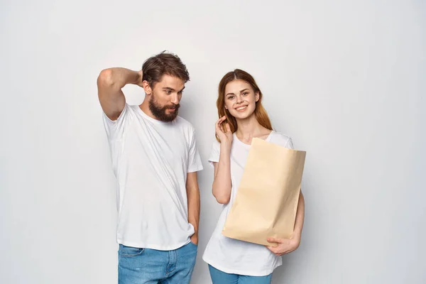 Mężczyzna i kobieta w białych t-shirtach zakupy torba papierowa — Zdjęcie stockowe