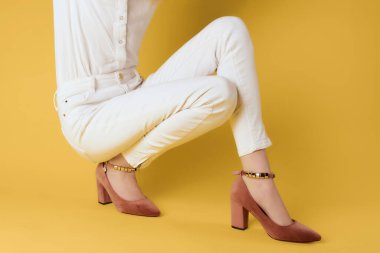 Stüdyo sarısı arka plan pozu veren şık giysili kadın.