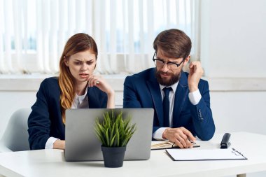 Yöneticiler ofiste bir dizüstü bilgisayarın önünde sohbet ediyorlar.