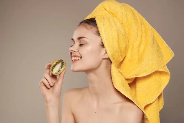 Kvinna med en handduk på huvudet med frukt kiwi i handen beskuren utsikt — Stockfoto