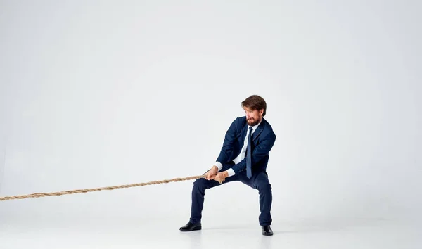 A man in a suit pulls the rope career office light background — Stock Photo, Image