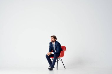 Kırmızı sandalyede oturan takım elbiseli bir iş adamı.