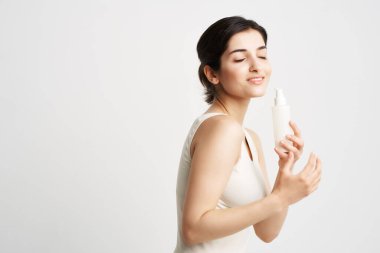 Beyaz kolsuz tişörtlü esmer, ellerinde losyon, temiz tenli.