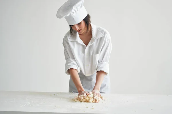 Wesoła kobieta piekarz w kucharzy mundur rolki ciasto na stole pracy — Zdjęcie stockowe