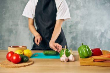 Mutfaktaki kadın sebze salatası kesiyor.