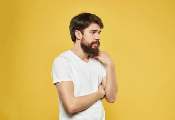 Férfi egy fehér póló expresszív megjelenés elégedetlenség sárga háttér — Stock Fotó