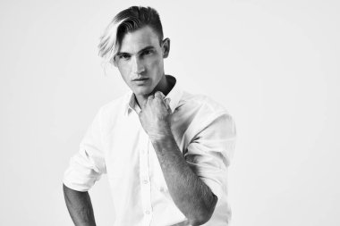 Beyaz gömlekli zarif bir adam. Saç stili. Kendine güven pozu veriyor.