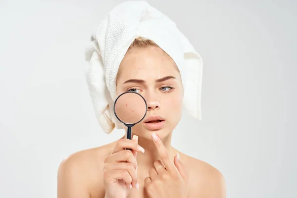 pretty woman with  naked shoulders holding magnifier near face