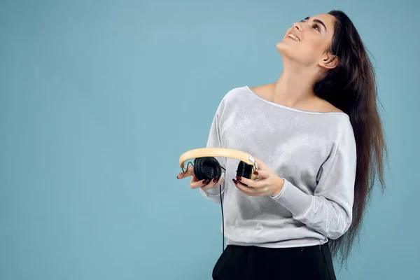 Morena bonita com fones de ouvido na mão tecnologia da música fundo azul — Fotografia de Stock