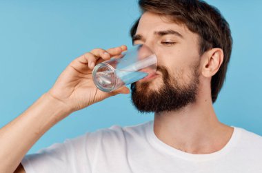Beyaz tişörtlü adam izole edilmiş arka planda bir bardak su içiyor. Yüksek kalite fotoğraf