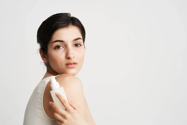 Kvinna i en vit t-shirt satte sig i händerna återfuktande hudvård — Stockfoto