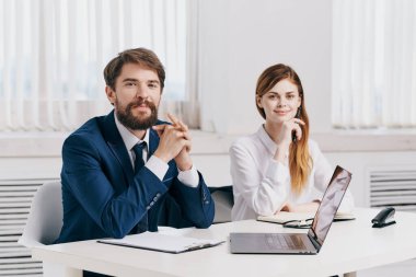 Laptop ofis teknolojisinin önünde iş arkadaşları konuşuyor.