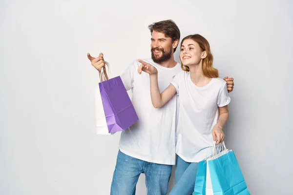 Молода пара в білих футболках з сумками в руках купує веселощі — стокове фото