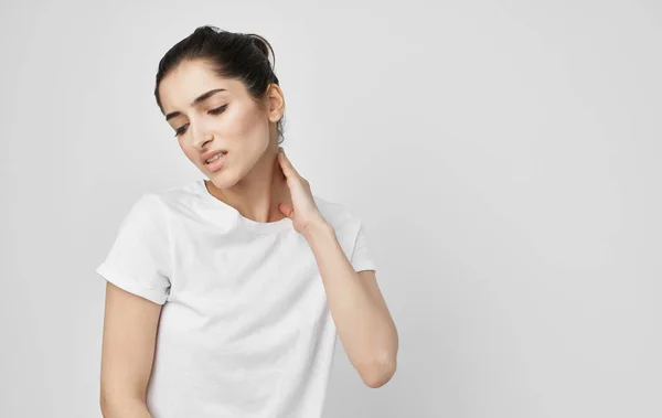 Brunette in a white t-shirt holds on to the neck treatment — Stock Photo, Image