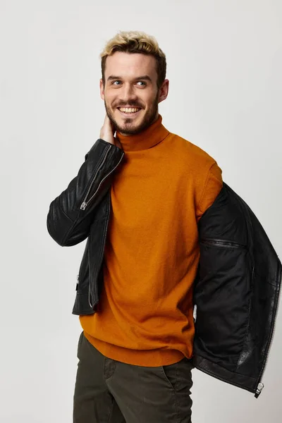 Gelukkig guy neemt uit zijn jas en oranje trui mouwen voor gezicht — Stockfoto
