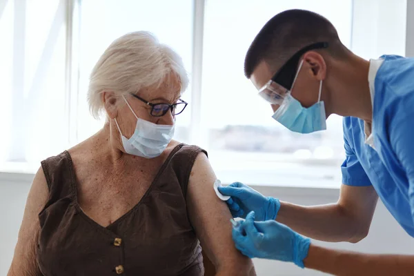 Man läkare bredvid en äldre kvinna covid-19 pass vaccination — Stockfoto