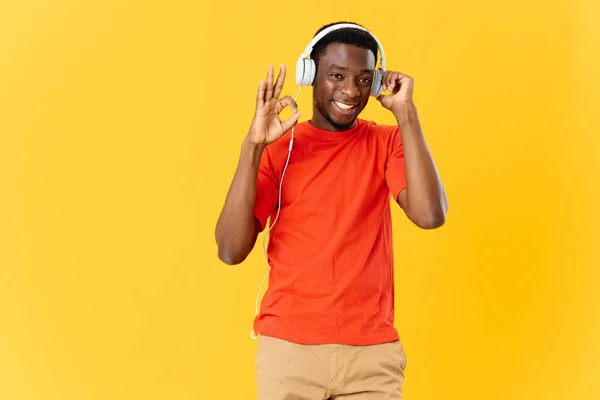 Homem alegre de aparência africana em fones de ouvido em um fundo amarelo — Fotografia de Stock