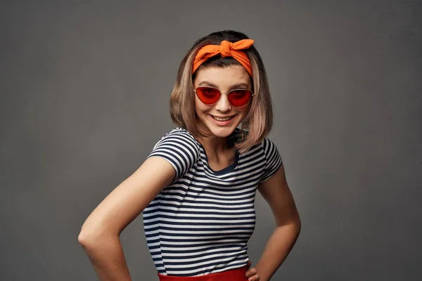 Femme en lunettes de soleil avec un bandage orange sur la tête dans un t-shirt rayé mode — Photo