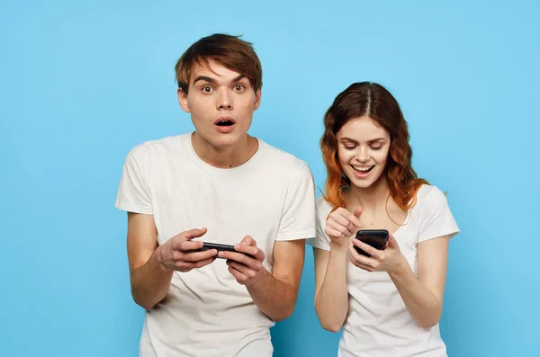 Giovane coppia con telefoni nelle mani aumento della tecnologia di comunicazione — Foto Stock