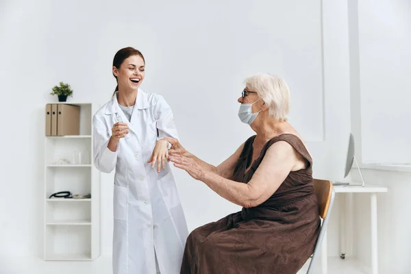 Sjuksköterska som ger injektion till en äldre kvinna med ett sprutsjukhus — Stockfoto