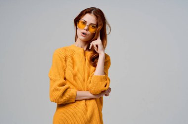 Sarı gözlüklü güzel kadın eğlenceli yaşam tarzı ışık arka planında poz veriyor.