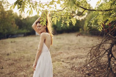 Beyaz elbiseli bir kadın doğa yürüyüşü yapıyor.