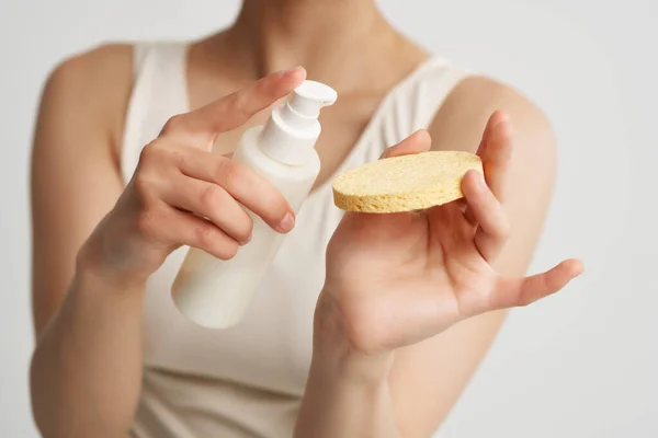 Mulher em t-shirt branca aplica loção em uma pele limpa esponja — Fotografia de Stock