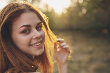 Açık havada poz veren kızıl saçlı bir kadın.