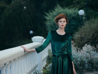 Bahçede yürüyen yeşil elbiseli kadın.