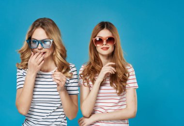 İki kadın çizgili tişörtlerin yanında modern moda kıyafetler giyiyor.