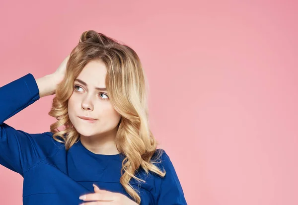 Hübsche Blondine im blauen Kleid hält die Haare Studio rosa Hintergrund — Stockfoto