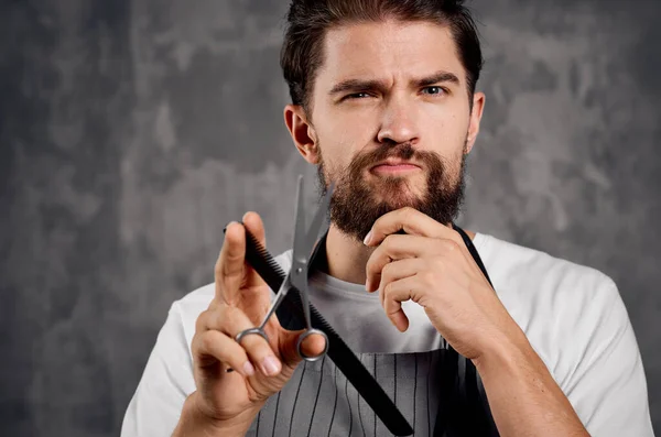 bearded male hairdresser in apron comb scissors service