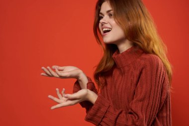 Kırmızı kazaklı neşeli kadın moda dekorasyonu yapıyor.