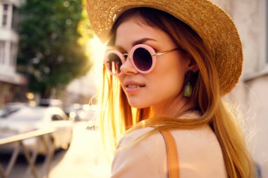 Güneş gözlüğü takan neşeli kadın yaz tatilinde dışarıda yürüyor.