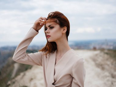 Güzel bir kadın kumsalda oturuyor. Çekici görünüyor.