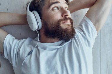 Kulaklık takmış, pencere eşiğinde uzanan genç bir adam.