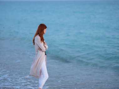 Kadın kıyı boyunca yürür. 