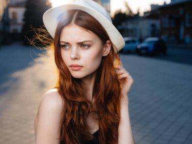 Açık havada poz veren şapkalı çekici kadın. 