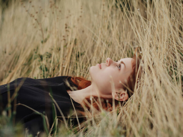 Woman in a black dress lies on the grass on nature