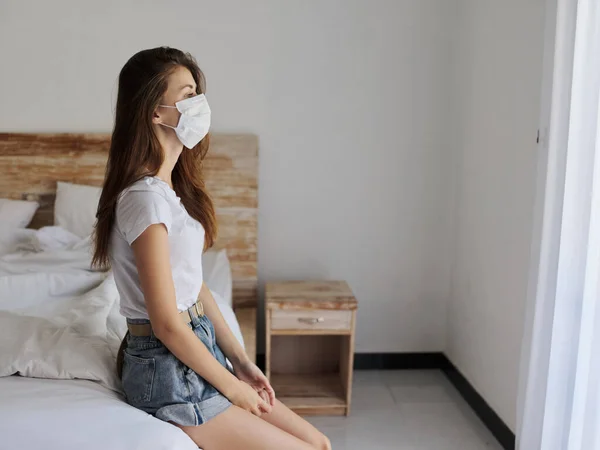 Woman on vacation sitting on bed indoors shelf medical mask — Stock Photo, Image