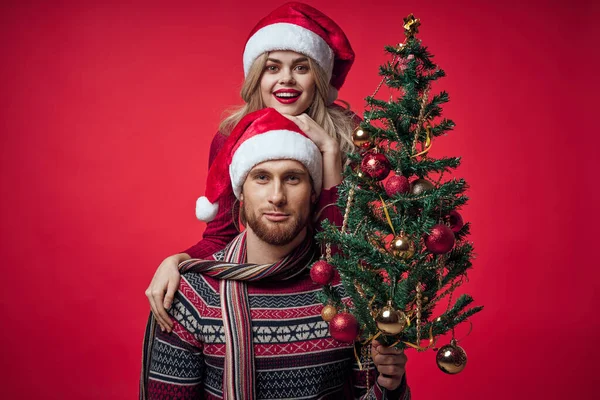 Άνδρας και γυναίκα χριστουγεννιάτικο δέντρο διακόσμηση διασκέδαση διακοπές κόκκινο φόντο — Φωτογραφία Αρχείου