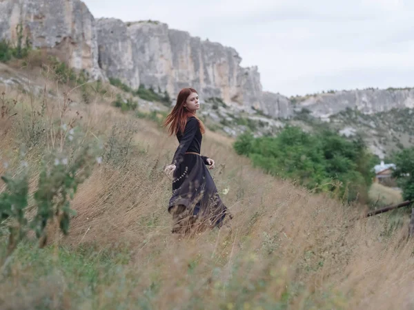 Mulher ruiva vestido preto andar montanhas liberdade — Fotografia de Stock