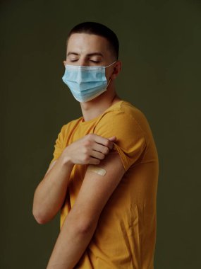 pareo sarı tişörtler, omuzlarında yapıştırıcı bantlı tıbbi maske, covid pasaport.