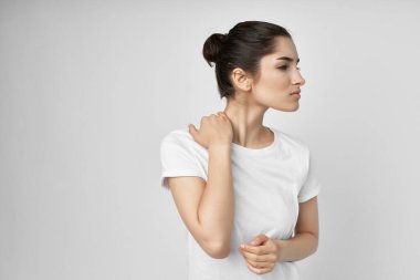 Esmer, beyaz tişörtlü, boynu ağrılı, izole bir arka plan.