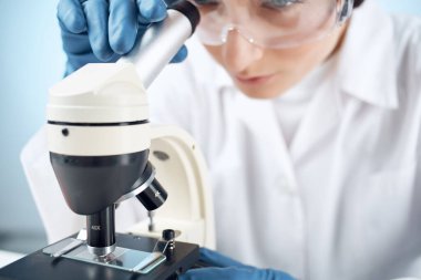Tıbbi eldivenler mikroskop biyoteknoloji tıbbında kadın laboratuvar asistanı.