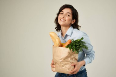 Markette sağlıklı sebzelerle dolu bir paketle esmer bir kadın.