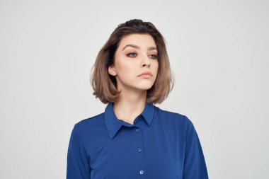 Mavi gömlekli, gözlüklü, moda stüdyosu olan bir iş kadını.