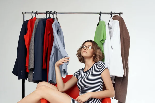 Vidám nő szemüveges próbál ruha bolt shopaholic fény háttér — Stock Fotó